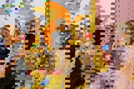 Een kinderleidster geeft vier kinderen muziekles met een bel